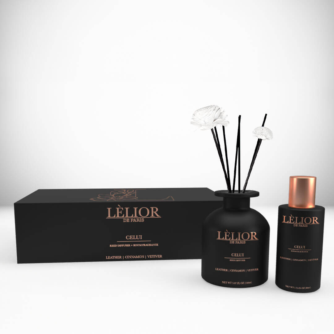 A luxury black box with a 150ml Celui reed diffuser and a 50ml Celui room spray. Black bottles with rose gold lettering and caps. Reed sticks. White background.